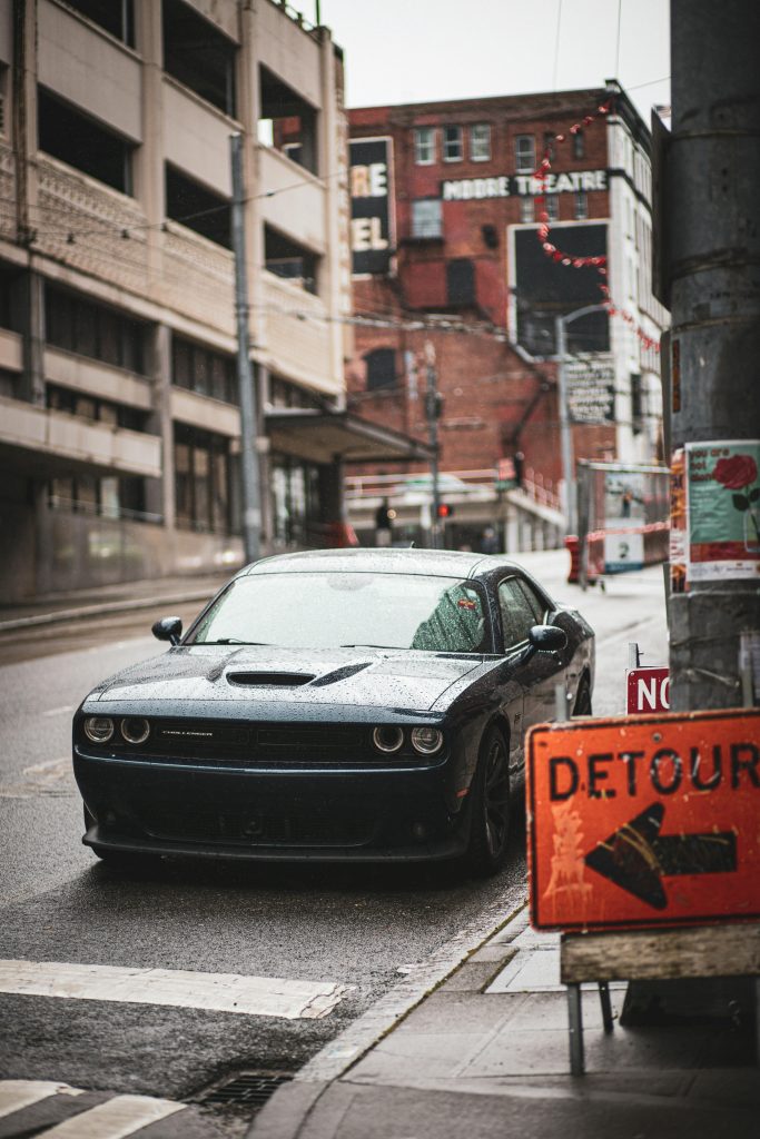 A Dodge Challenger parked on a rainy Seattle street, reflecting urban life.